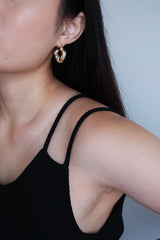 Black hair woman wearing twisted shiny hoops