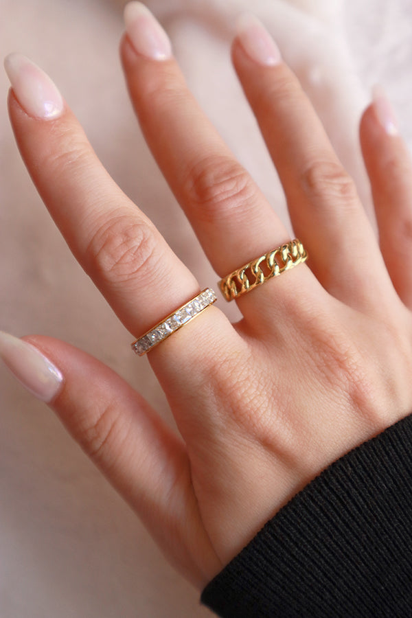 Woman stacking shining gold ring and chain ring on the right hand