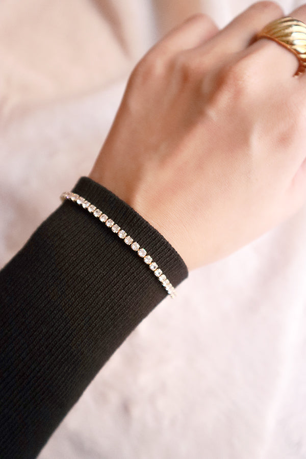 Woman in black dress wearing a rhinestone bracelet and 18K gold rings