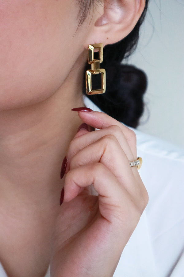 Woman in white shirt wearing SH&Co. square drop earrings