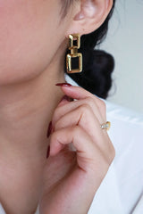 Woman in white shirt wearing SH&Co. square drop earrings
