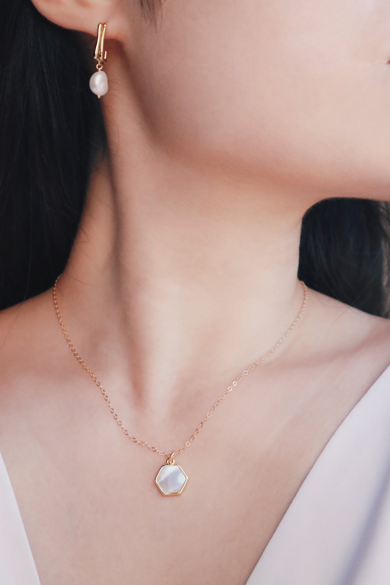 Fresh water pearl earrings and mother of pearl necklace under spotlight