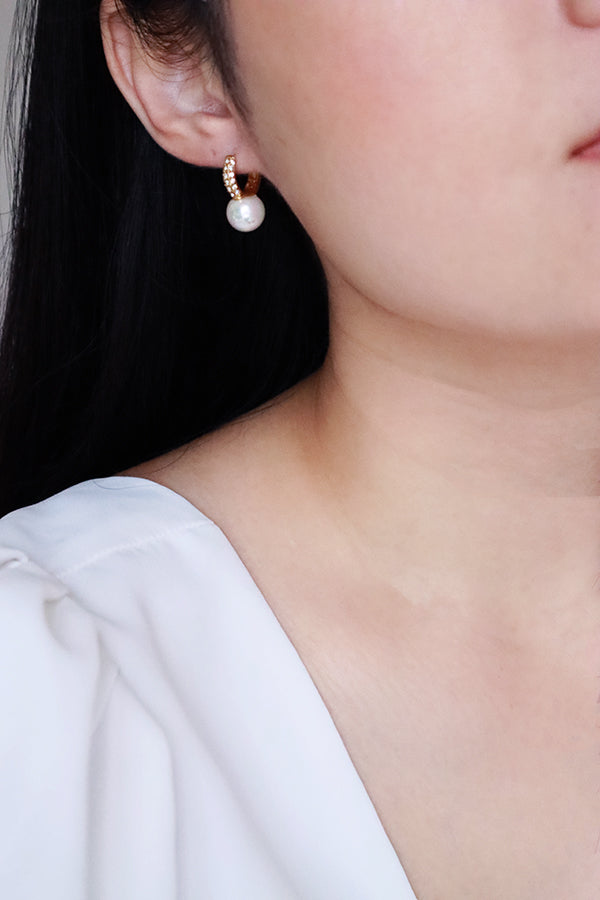 Woman in white dress wearing shell pearl cz hoop earrings