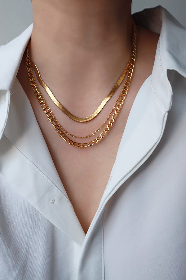 Woman layering herringbone necklace and figaro necklace