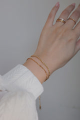 Woman stacked two types of gold chain bracelets together