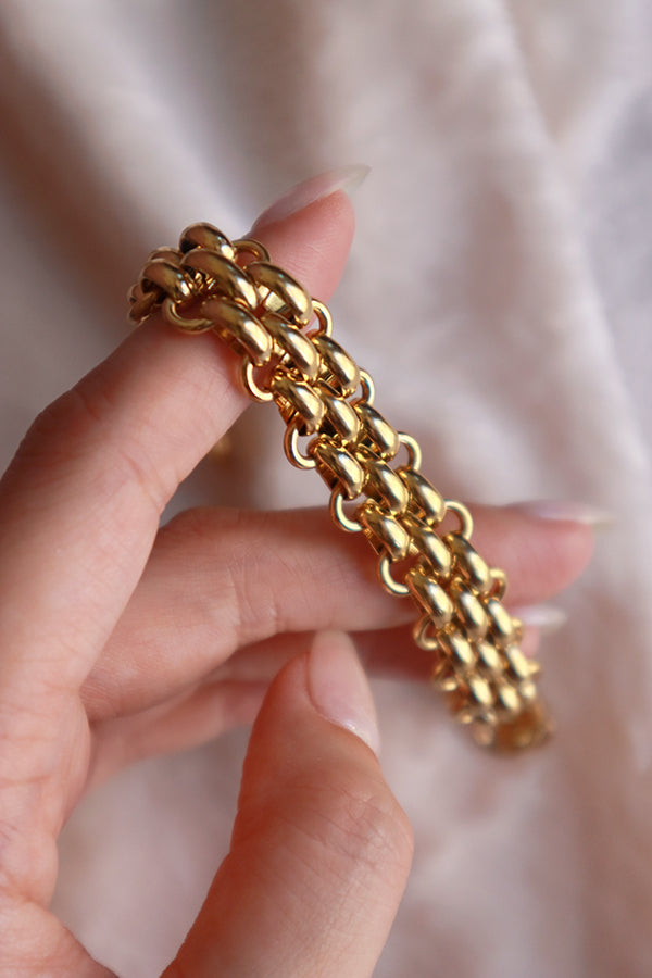 Woman holding a gold bracelet shows the details to camera