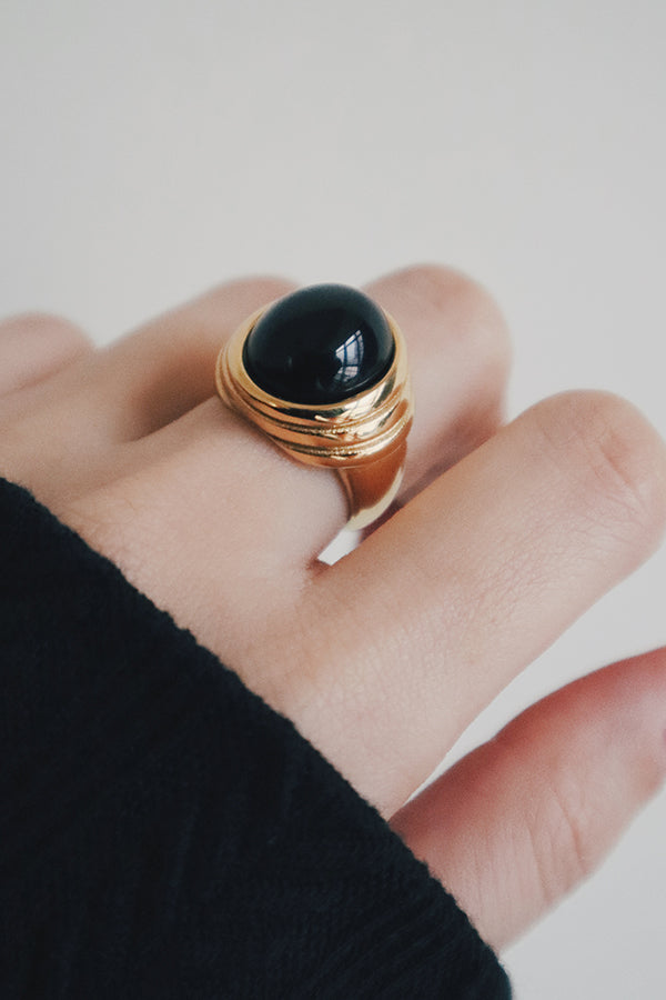Woman showing trendy gemstone gold ring to camera