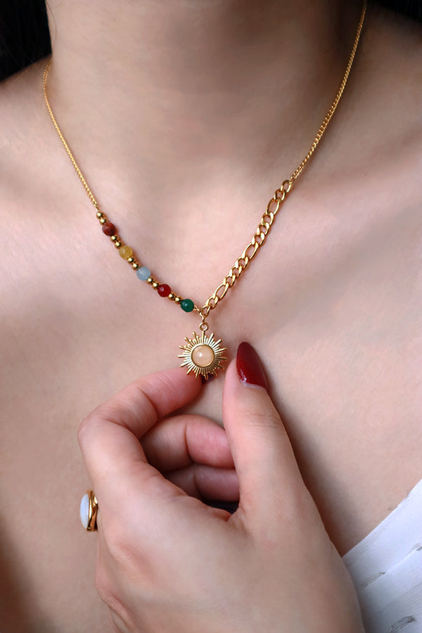 Woman with red nails touching the opal stone sun necklace