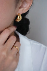 Model in white shirt wearing trendy croissant gold earrings